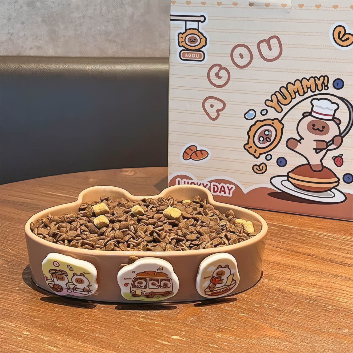 slow feeder and pet food next to a cartoon-themed box on a wooden surface