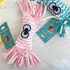 The bright strawberry pink variant of the Woven Candy Squeaky Toy. The close-up shows the wrapped candy shape, the thick braided fabric texture, and the large cartoon eyes.