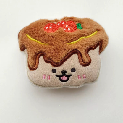 A soft strawberry pudding cake plush toy featuring a chocolate drizzle design and two embroidered strawberries.