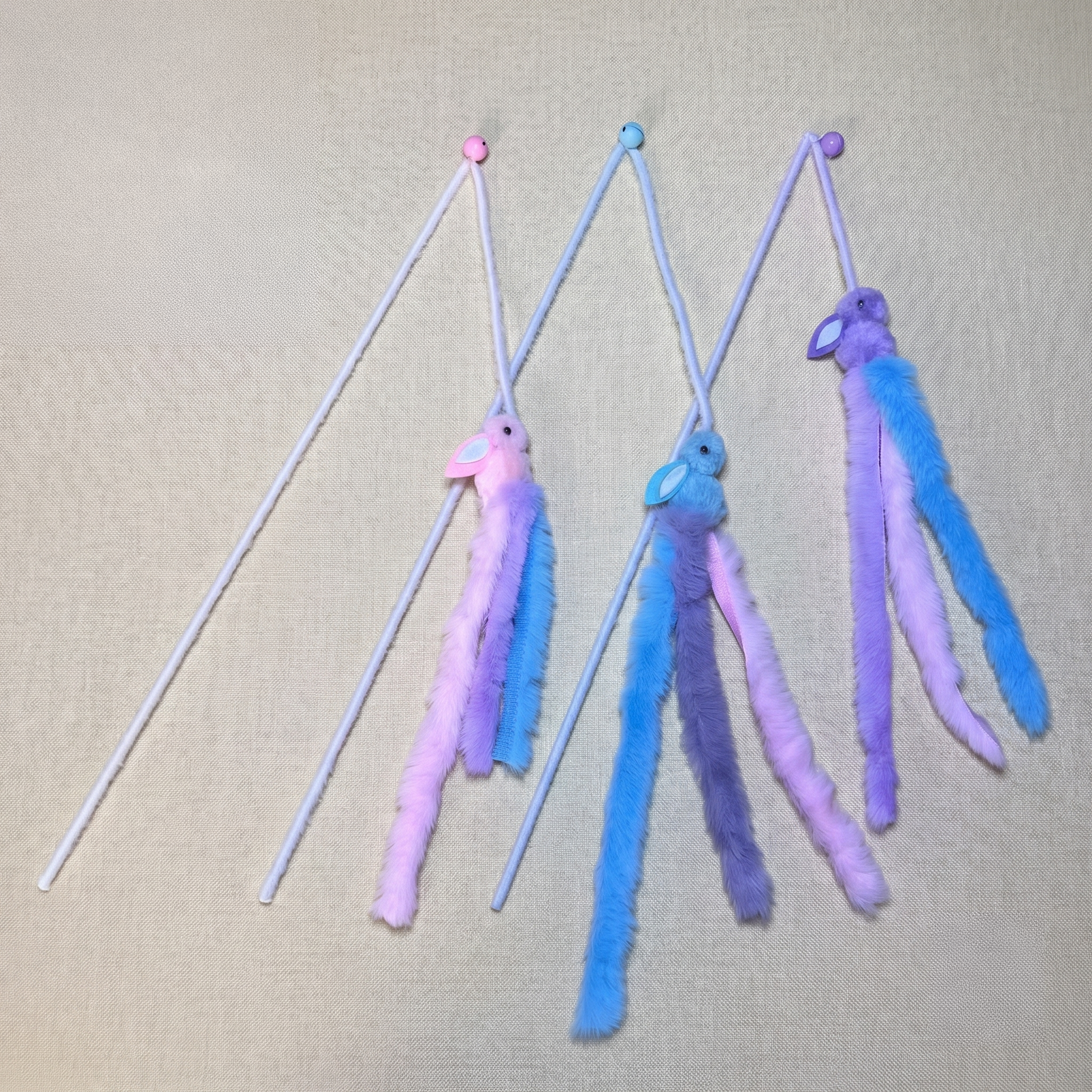 cat teaser wands featuring plush bunny heads with long fleece tails and bells.