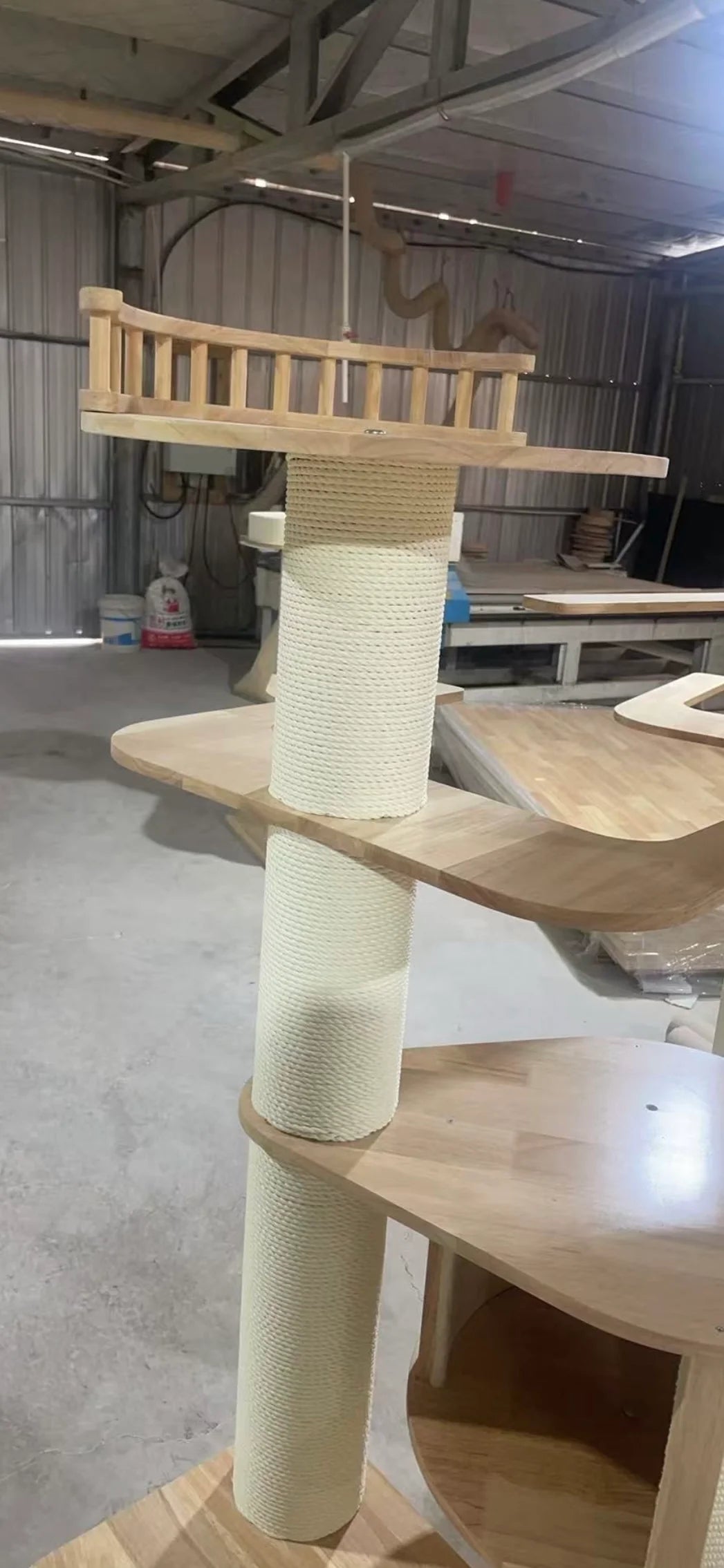 A close-up view of the TORA 2501 PRO cat tree taken in a workshop, focusing on the solid wood Fence Top configuration that provides extra security and a cozy penthouse feel for climbing cats.
