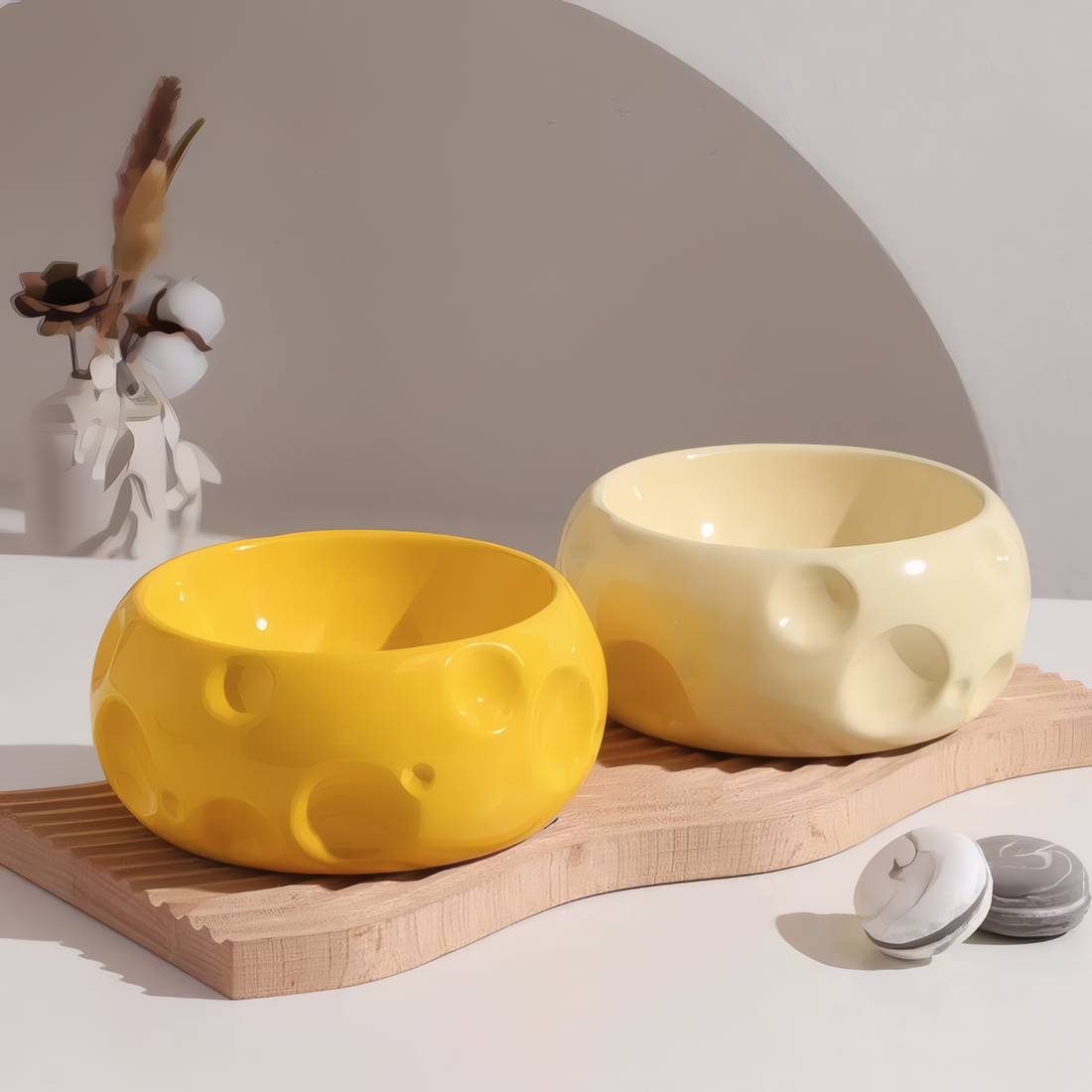 Two ceramic bowls, one yellow and one beige, on a wooden board with a neutral background.