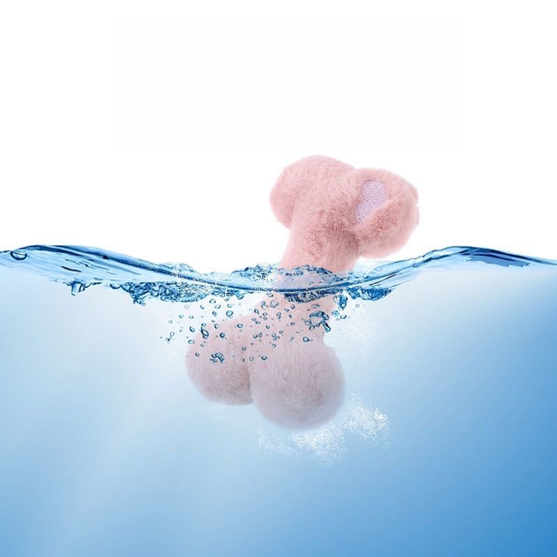 A pink plush bone dog toy partially submerged in clear, splashing blue water, demonstrating that the premium fabric and internal squeaker are fully washable and easy to clean.