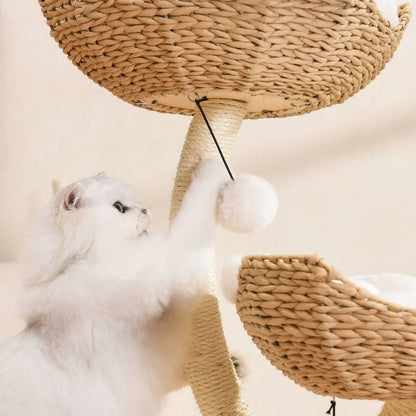 A fluffy white cat standing on its hind legs to playfully swat at a dangling white pom-pom toy attached beneath a basket on the Michu Ivy cat tower.