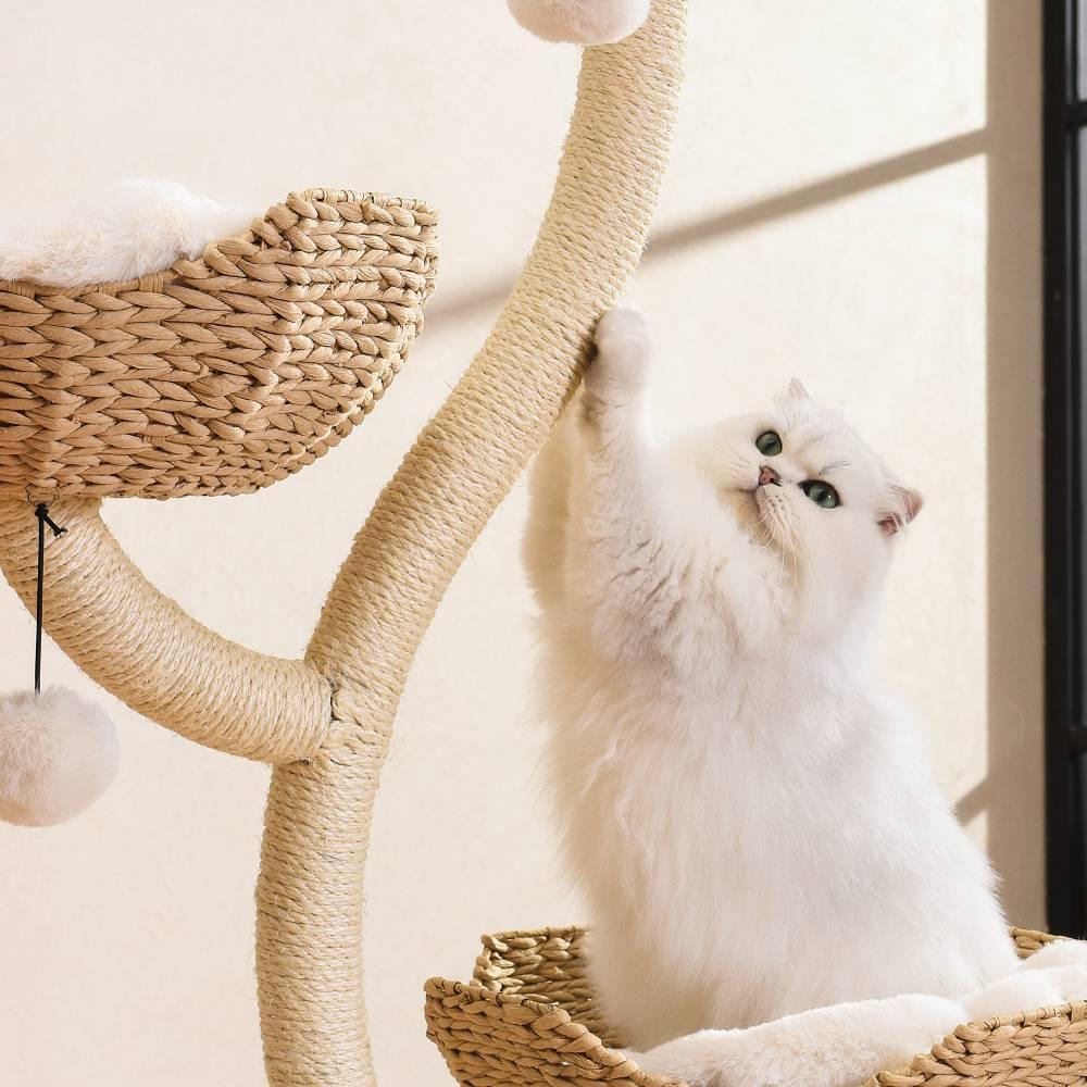 A fluffy white cat sitting comfortably in a handwoven basket on the Michu Ivy cat tree, reaching up to fiercely scratch the thick sisal rope post.
