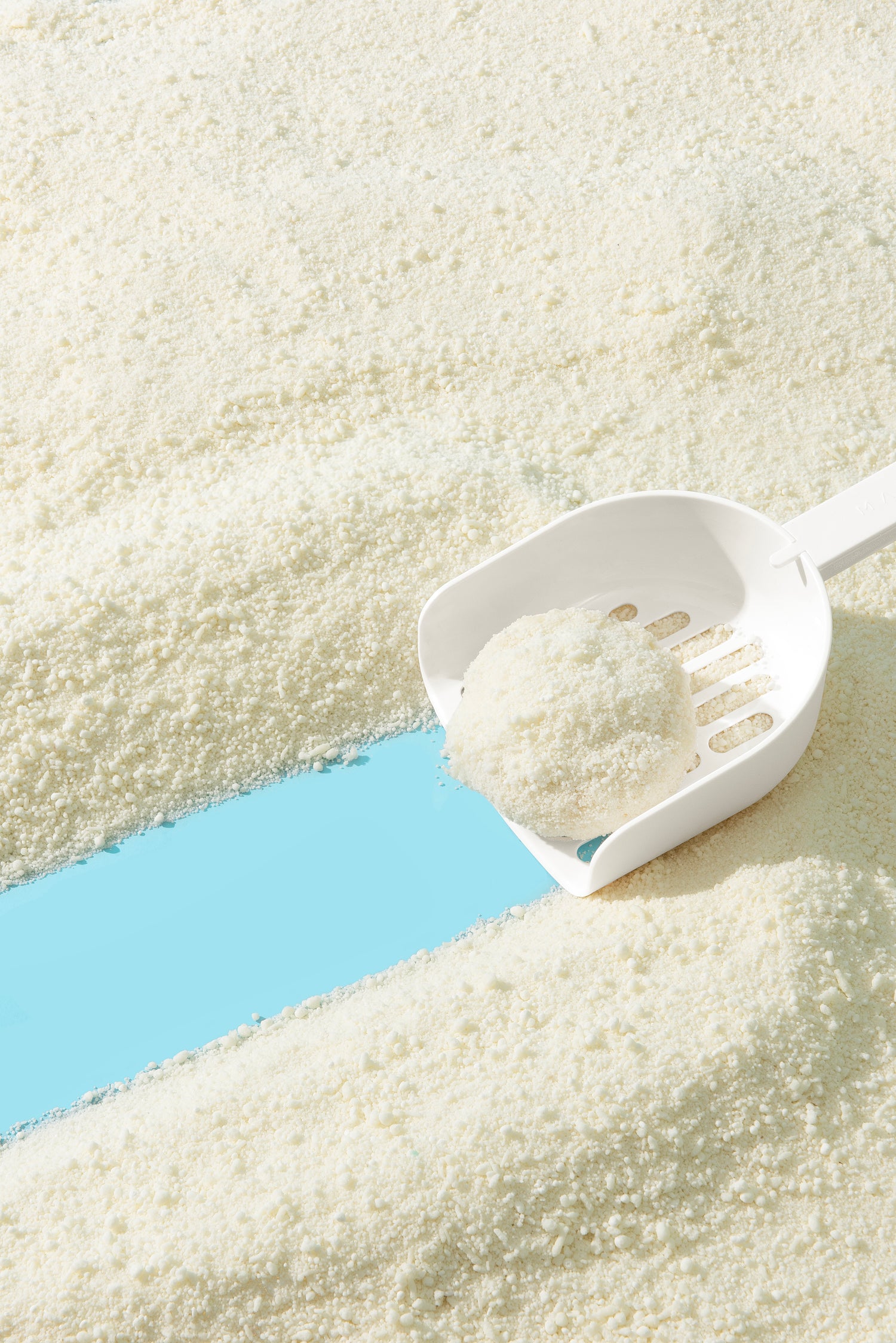 White scoop with a scoop of cat litter on a litter surface